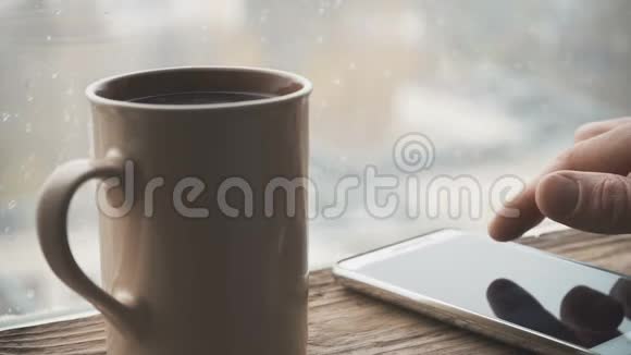 陶瓷杯手机放在窗台上靠窗下雨滴视频的预览图
