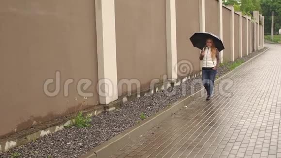 带着雨伞在公园雨天散步的女孩视频的预览图