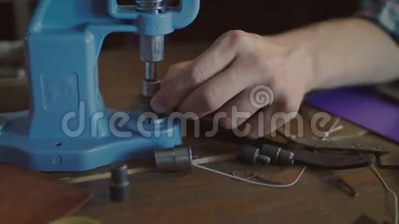 工人在皮带上插入金属按钮皮革配件制造视频的预览图