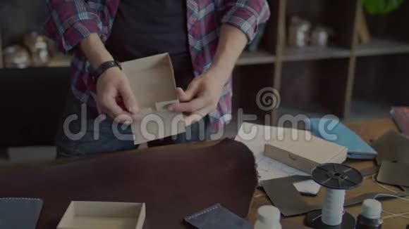 手工工人制作纸板箱并将皮革附件放入包装中视频的预览图