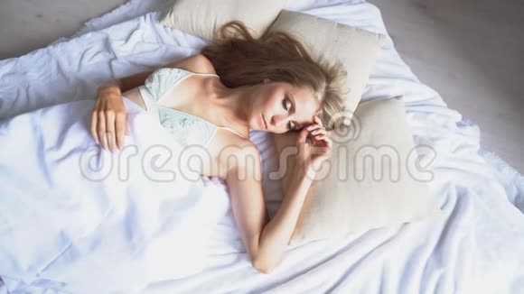 早晨美丽的女孩在他的床上醒来视频的预览图