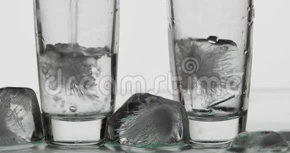 把两杯伏特加从瓶子里倒入玻璃杯里白色背景视频的预览图