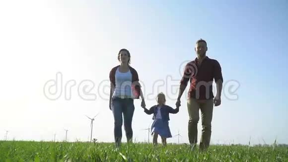 爱的父母和他们的女儿沿着绿色的草地走到镜头前视频的预览图