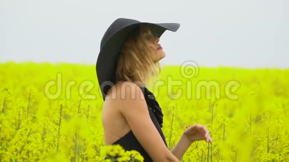 一个女孩在一个阳光明媚的下午在油菜花田里视频的预览图