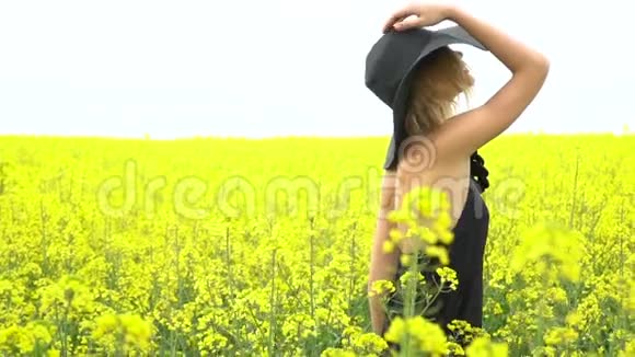 穿黑色衣服的女孩在卡诺拉的田野里摆姿势视频的预览图