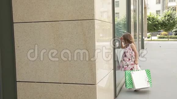 小女孩看着购物中心附近的窗户视频的预览图