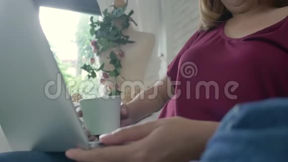 年轻的亚洲女人为她的生意做研究工作微笑的女人坐在沙发上放松一边浏览网上购物视频的预览图