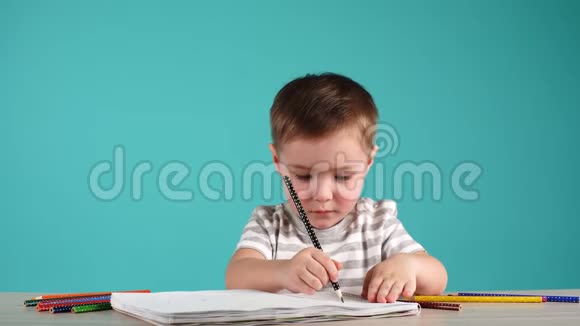 快乐的孩子用铅笔在相册里画画孤立在蓝色上视频的预览图