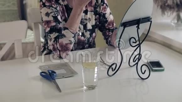 一位老妇人看着镜子里的皱纹从化妆品中清除皮肤面部护理整形外科和视频的预览图