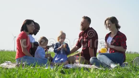 有孩子在野餐时休息的人笑着喝水果水慢动作视频的预览图