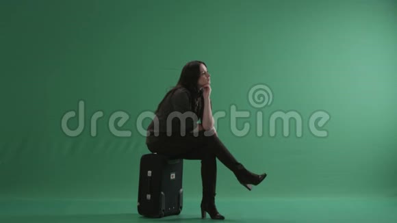 年轻的白种人女人坐在手提箱上思考视频的预览图