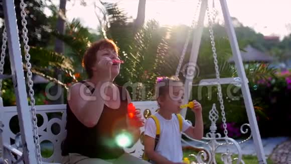 幸福微笑的家人奶奶带着孙女正在玩耍在夏天的户外吹肥皂泡股票视频的预览图