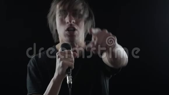 男摇滚歌手在黑色背景下对着麦克风唱歌视频的预览图