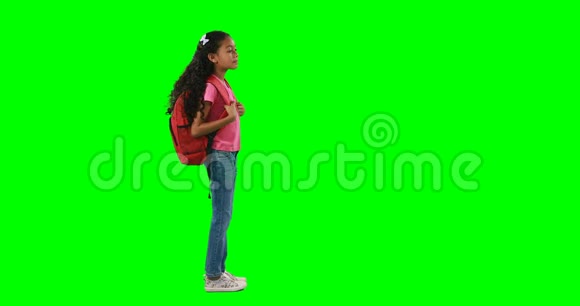 背着书包站在绿色背景下的女孩视频的预览图