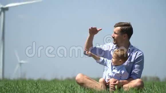男孩向坐在草地上的父亲展示了一些东西视频的预览图