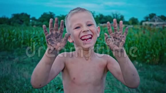 一个快乐的孩子露出肮脏的双手笑着一个男孩涂在泥里一个快乐的童年消遣视频的预览图
