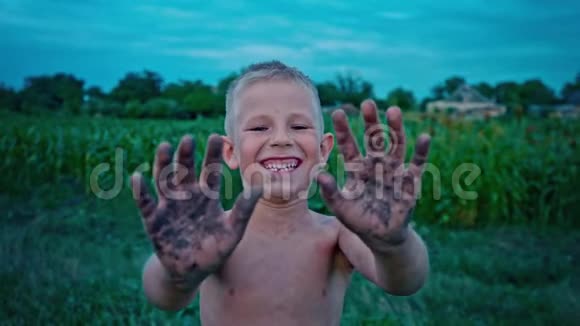 一个快乐的孩子露出肮脏的双手笑着一个男孩涂在泥里一个快乐的童年消遣视频的预览图