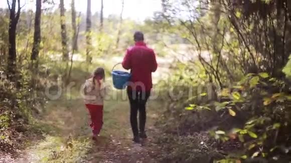 秋天年轻漂亮的妈妈和女儿带着篮子在森林里散步寻找蘑菇背面视频的预览图