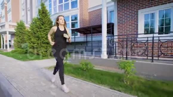夏天女运动员在街上的人行道上阳光下奔跑视频的预览图