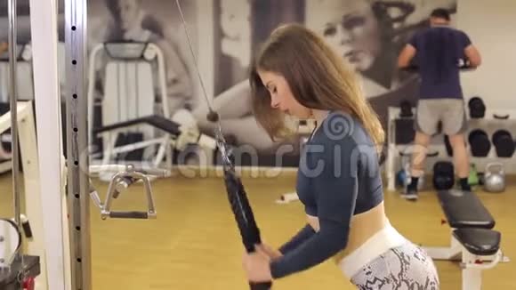 一个苗条强壮的女孩在健身房训练三头肌视频的预览图