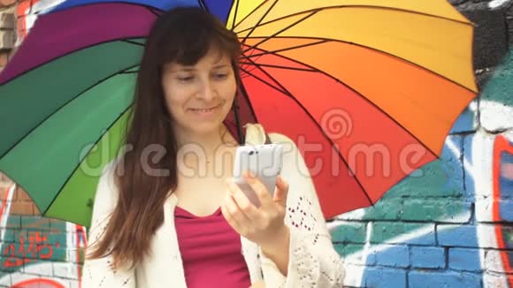 带伞的女人在墙旁边用一个涂鸦的电话视频的预览图