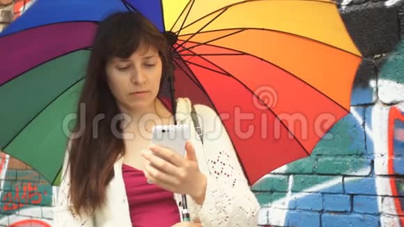 带伞的女人在墙旁边用一个涂鸦的电话视频的预览图