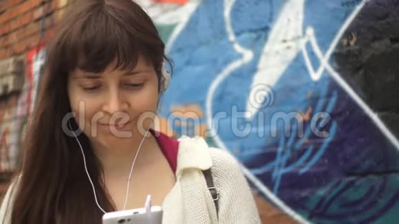 年轻女子在砖墙背景下听音乐跳舞视频的预览图