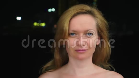 一个没有化妆的年轻女人的肖像裸露的肩膀抵着城市模糊的灯光复制空间视频的预览图