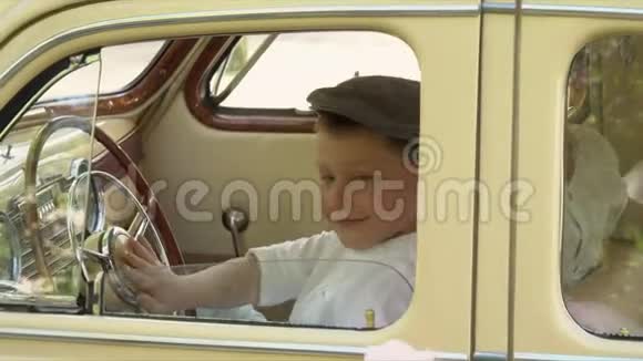 小男孩在一辆复古大轿车里玩搭车视频的预览图