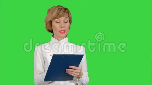 年轻漂亮的女商人穿着西装微笑着快乐着拿着平板电脑工作在绿色的屏幕上写着一条信息视频的预览图