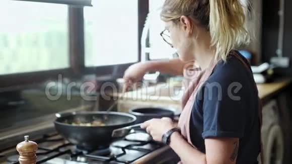 金发女人用煎锅准备一道菜视频的预览图