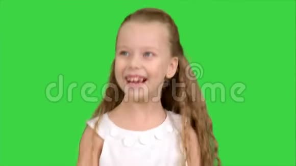 穿着白色连衣裙的小女孩喜欢在绿色屏幕上玩游戏颜色键视频的预览图