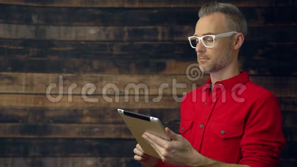 穿红色衬衫的体贴的嬉皮士用平板电脑视频的预览图