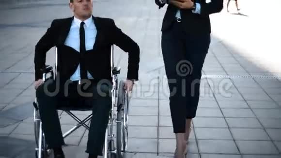 轮椅上的Crippb老板企业家给他的女商人用IPAD做指示视频的预览图