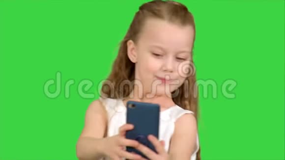 年轻女孩看着镜头微笑着在绿色屏幕上自拍色度键视频的预览图