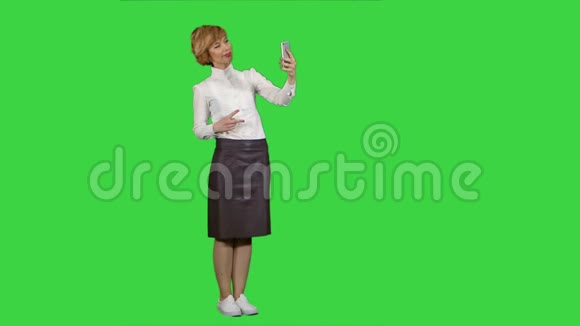 微笑可爱的女人在智能手机上的绿色屏幕上自拍照片色度键视频的预览图