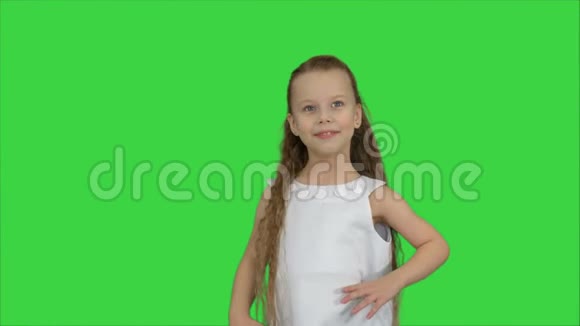 快乐美丽的小女孩在绿色屏幕上对着相机摆姿势色度键视频的预览图