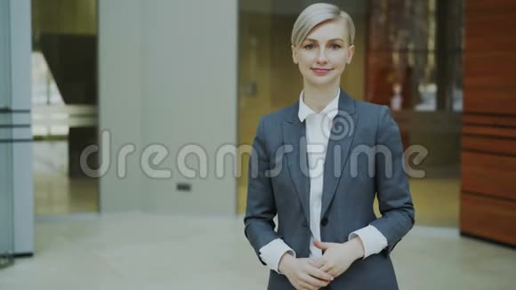 现代办公室里成功的金发女商人微笑着看镜头的肖像视频的预览图