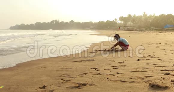 女孩独自在岸边玩沙子视频的预览图