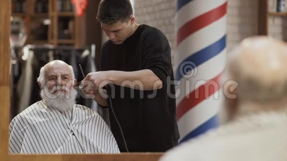 发型师在理发店剪成熟男人的白发视频的预览图