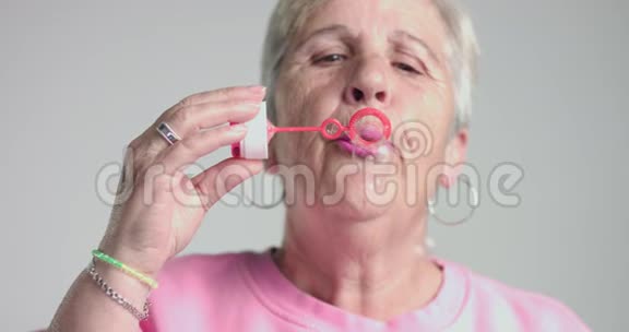 年长的女人吹泡泡到相机上视频的预览图