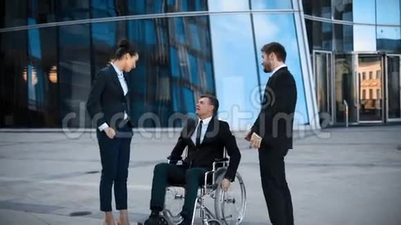 坐轮椅的跛脚商人和他的两个同事之间正面的谈话视频的预览图