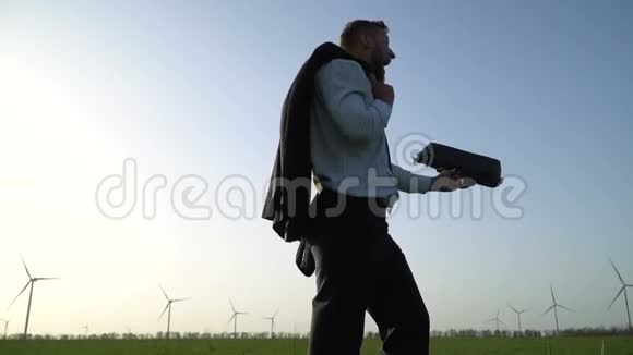 一个穿着商务服的男人走在绿色的草地上挥舞着一个公文包视频的预览图