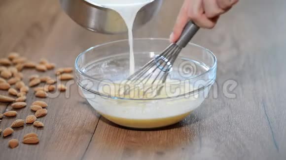 一个女人在厨房里做奶油冻碗里倒着牛奶视频的预览图