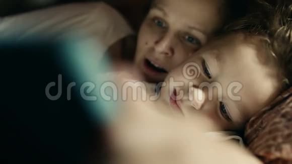 母亲和儿子在睡前玩平板电脑视频的预览图