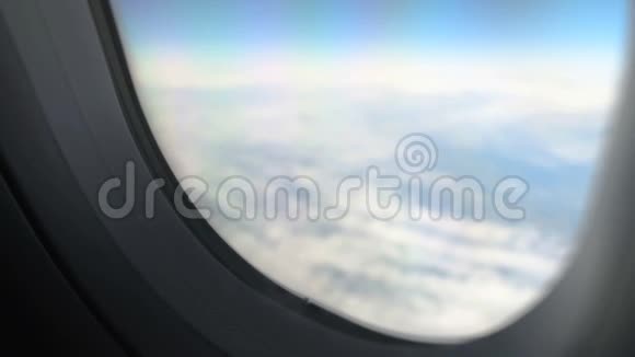 在宁静的天空中透过飞机在云层上方飞行的窗口观看空中运输视频的预览图