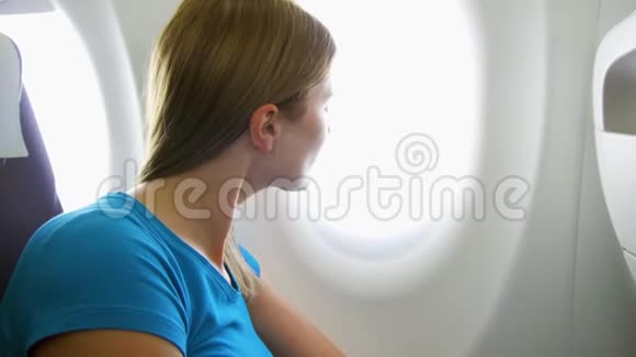 白天坐飞机的女人在湍流中女性在靠近窗户时感到疲倦视频的预览图