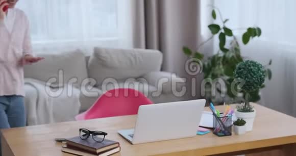微笑的女商人用手机和笔记本电脑说话视频的预览图