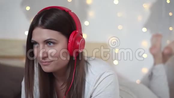 一个漂亮的女孩躺在床上用手机电脑用耳机听音乐高清高清视频的预览图