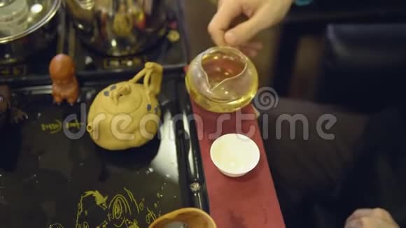 茶道大师把绿茶从玻璃茶壶倒入白色杯子视频的预览图